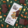 Theo Almond Brittle Crunch 55% Dark Chocolate Bar with handmade brittle pieces on green background