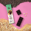 Theo Chocolate Peanut Butter Brittle 70% Filled Dark Chocolate with ingredients on pink background
