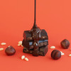 Theo Chocolate Hazelnut Crisp 70% Filled Dark Chocolate unwrapped with chocolate pouring over on red background