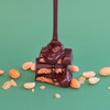 Theo Chocolate Peanut Butter Brittle 70% Filled Dark Chocolate unwrapped with chocolate pouring over on green background
